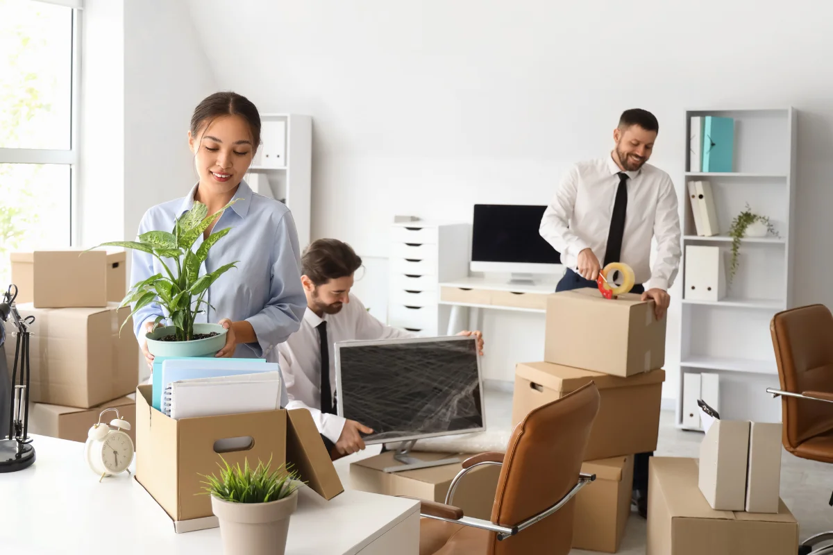 Office movers packing computers desks and office supplies for secure relocation